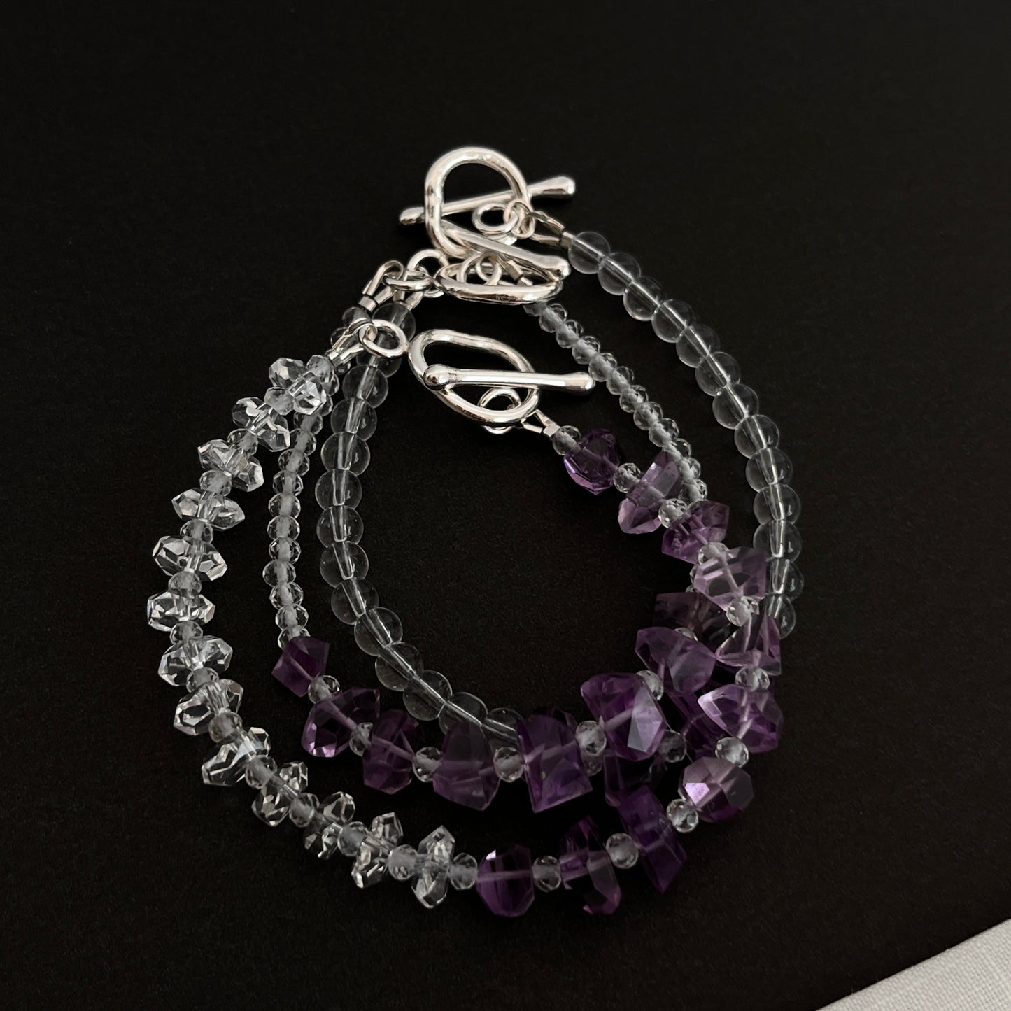 Stack of beaded bracelets with silver clasps on a black background